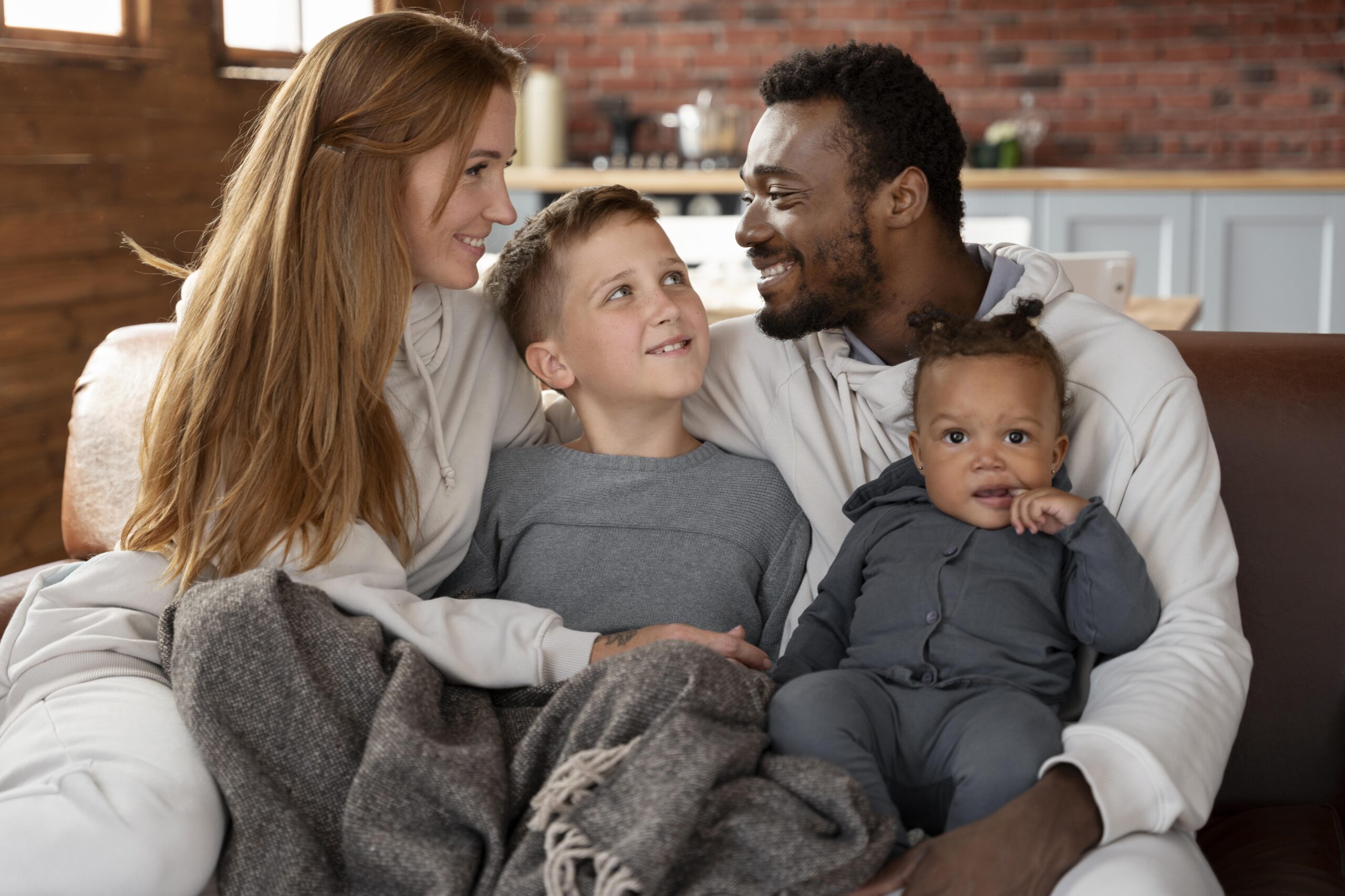 Famille souriante réunie sur un divan, les parents regardant leurs enfants